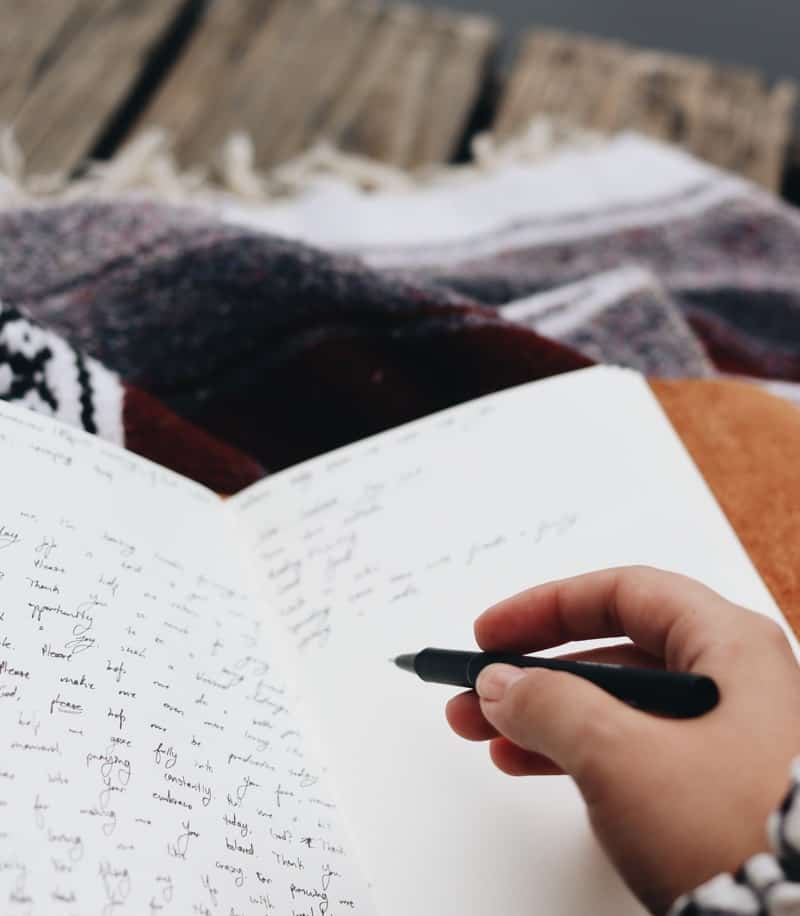 girl writing in manifestation journal